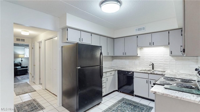 kitchen with black appliances, tasteful backsplash, a sink, and visible vents