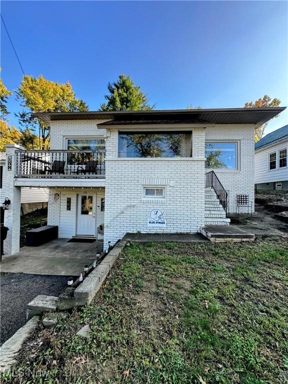 view of front of home featuring brick siding and a balcony