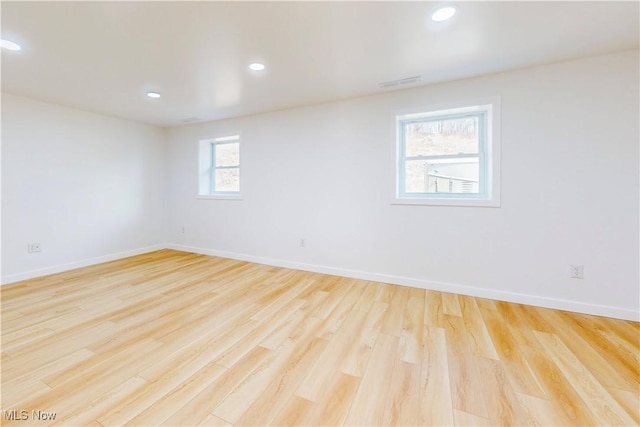 spare room featuring light wood-type flooring, baseboards, visible vents, and recessed lighting