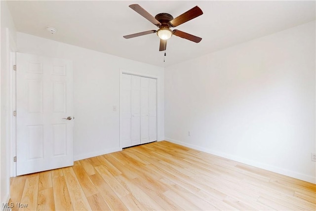 unfurnished bedroom featuring light wood-type flooring, a ceiling fan, baseboards, and a closet