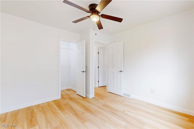 unfurnished room with light wood-style floors, ceiling fan, visible vents, and baseboards