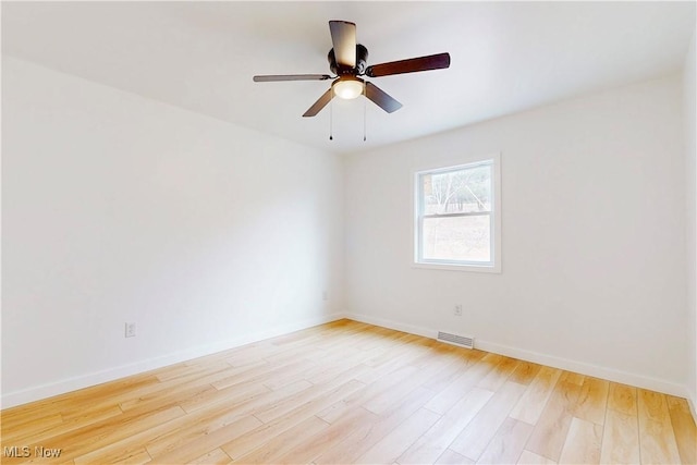 empty room with baseboards, visible vents, and light wood finished floors