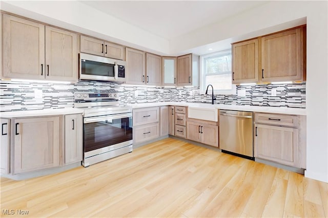 kitchen with appliances with stainless steel finishes, light countertops, light wood finished floors, and light brown cabinetry