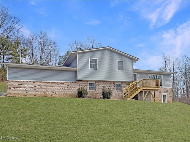 rear view of property with stairs, a yard, a deck, and brick siding