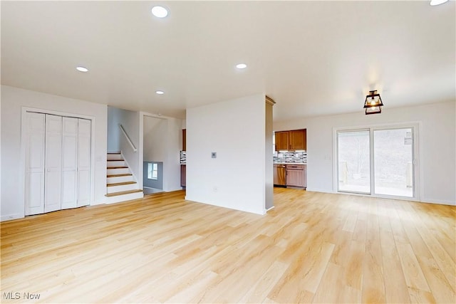 unfurnished living room featuring stairs, light wood-style flooring, and recessed lighting