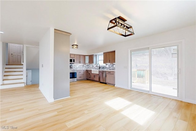 kitchen featuring light wood finished floors, tasteful backsplash, light countertops, range, and dishwasher