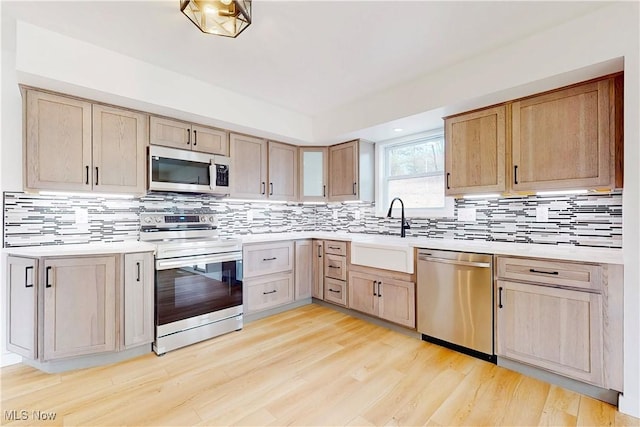 kitchen featuring light brown cabinets, light countertops, appliances with stainless steel finishes, and a sink