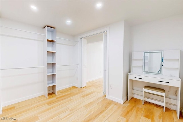 walk in closet with light wood-style floors