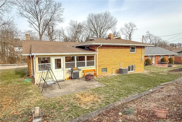 rear view of property featuring a patio area, an outdoor fire pit, a chimney, and brick siding