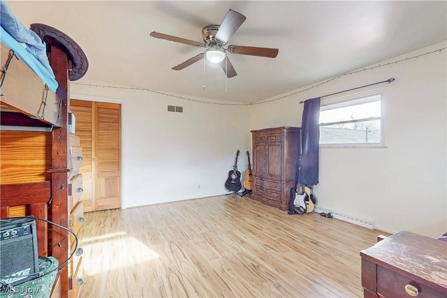 bedroom featuring a ceiling fan, visible vents, and wood finished floors