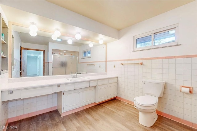 full bath with tile walls, toilet, vanity, a shower stall, and wood finished floors