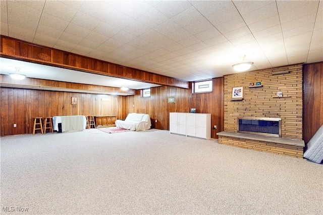 unfurnished room featuring wood walls, carpet flooring, and a stone fireplace