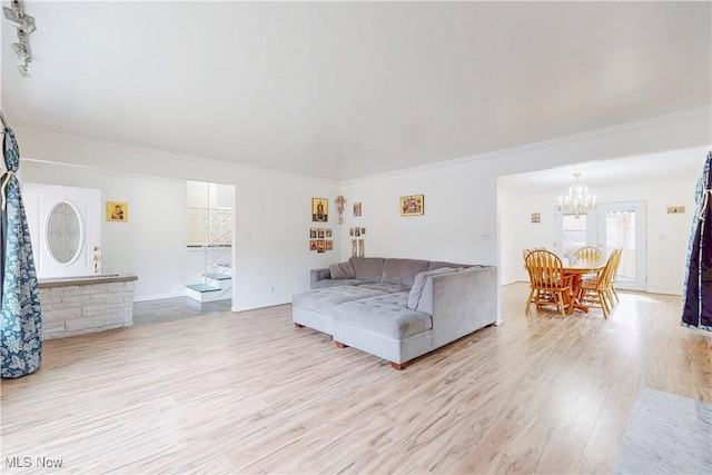 living room featuring light wood-type flooring, ornamental molding, and a chandelier