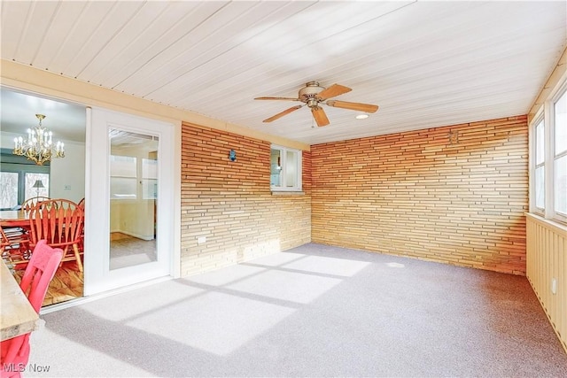 sunroom featuring ceiling fan with notable chandelier and a healthy amount of sunlight