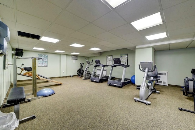 gym featuring baseboards, a paneled ceiling, and radiator