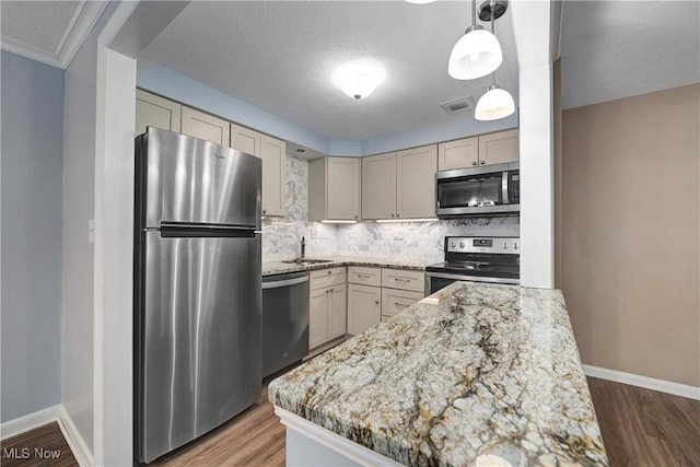 kitchen featuring stainless steel appliances, wood finished floors, visible vents, backsplash, and light stone countertops