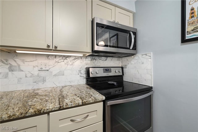 kitchen featuring stainless steel appliances, tasteful backsplash, white cabinetry, and light stone countertops