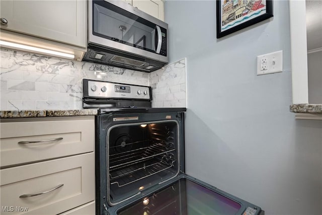 kitchen featuring stone counters, electric stove, stainless steel microwave, and backsplash