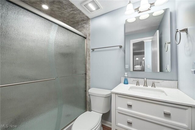 bathroom featuring visible vents, a shower stall, toilet, and vanity