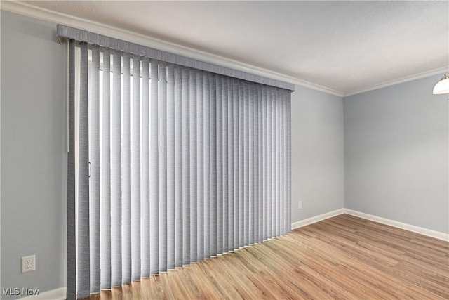 unfurnished room featuring baseboards, ornamental molding, and wood finished floors