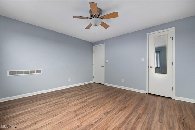 unfurnished room featuring ceiling fan, wood finished floors, visible vents, and baseboards