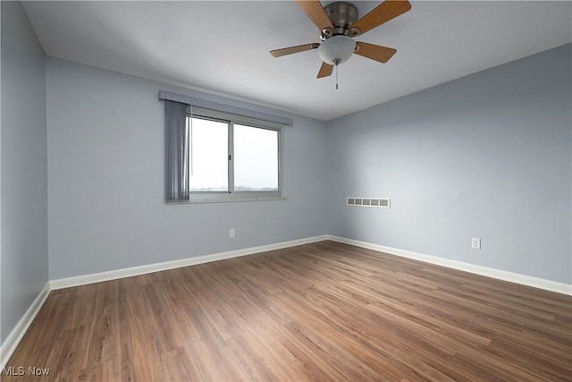 empty room with a ceiling fan, visible vents, baseboards, and wood finished floors