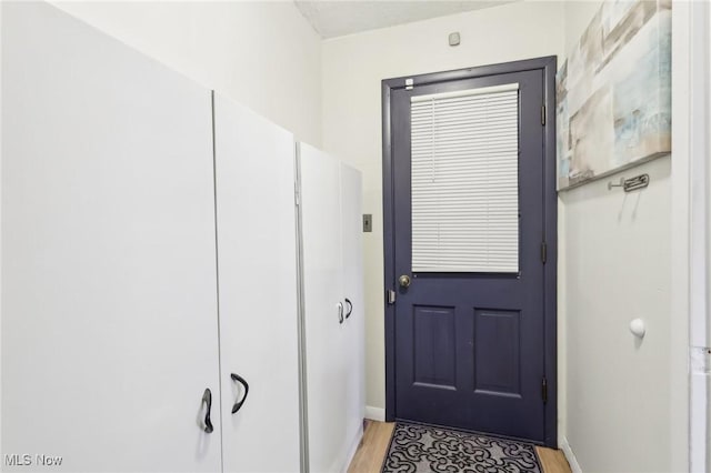 doorway featuring baseboards and light wood-style floors