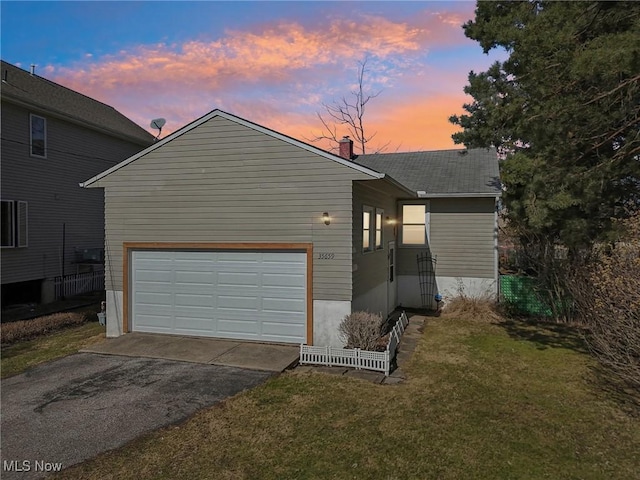 view of front of house with a garage, driveway, and a lawn