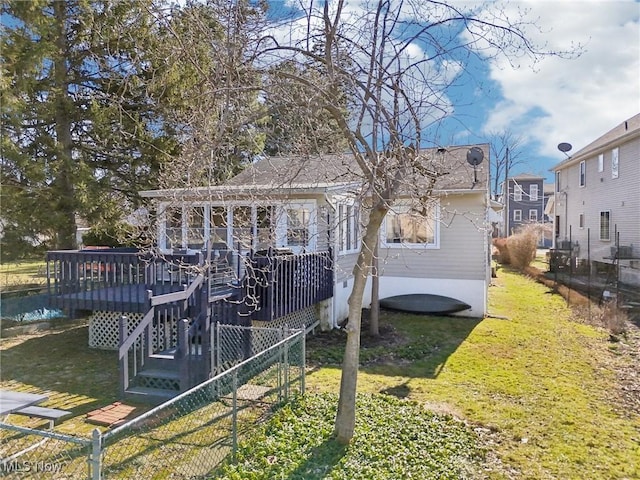 rear view of property with a yard, fence, and a wooden deck