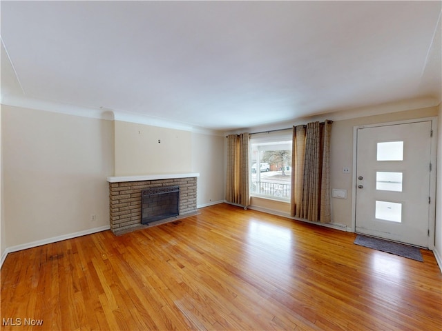 unfurnished living room with baseboards, a fireplace, and light wood finished floors