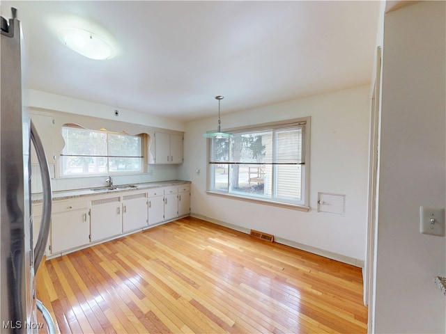 kitchen featuring a sink, visible vents, light wood-style floors, light countertops, and freestanding refrigerator