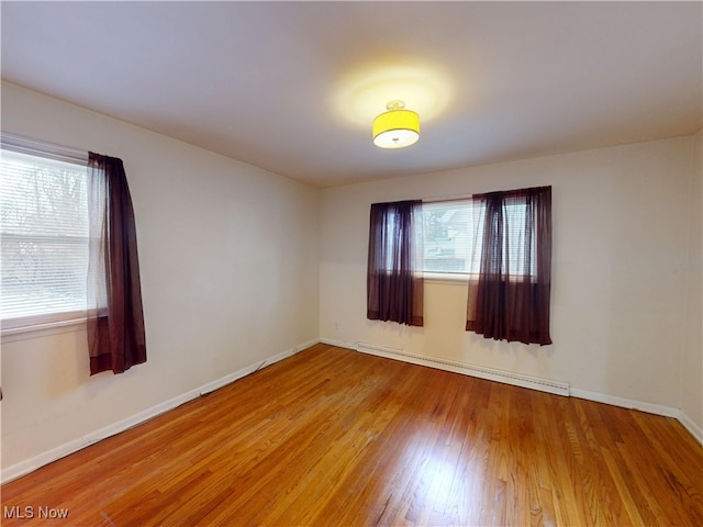 empty room featuring baseboards, baseboard heating, and wood finished floors