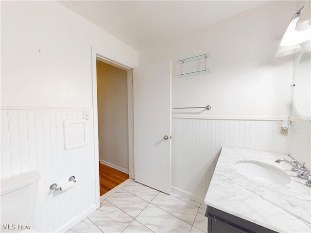 bathroom featuring wainscoting, vanity, and toilet