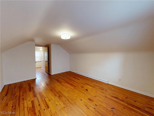 bonus room featuring a baseboard heating unit, light wood finished floors, vaulted ceiling, and baseboards