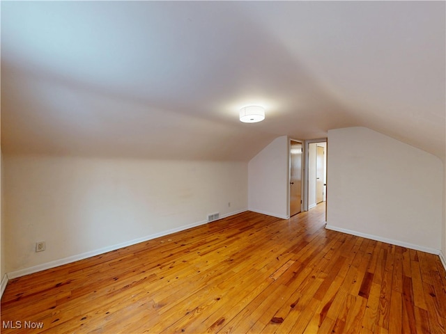 bonus room with vaulted ceiling, light wood finished floors, visible vents, and baseboards