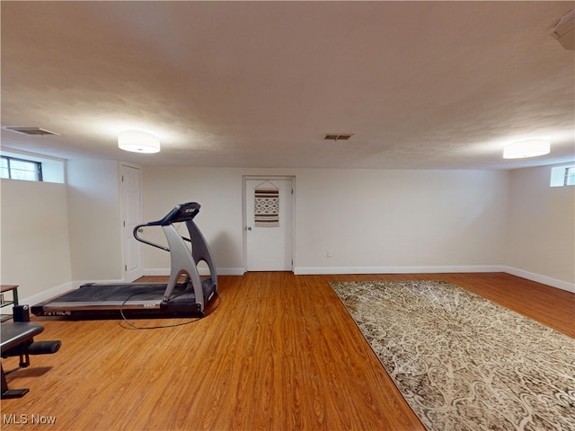 exercise room featuring visible vents, baseboards, and wood finished floors