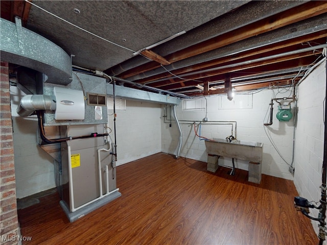 basement featuring visible vents, a sink, and wood finished floors