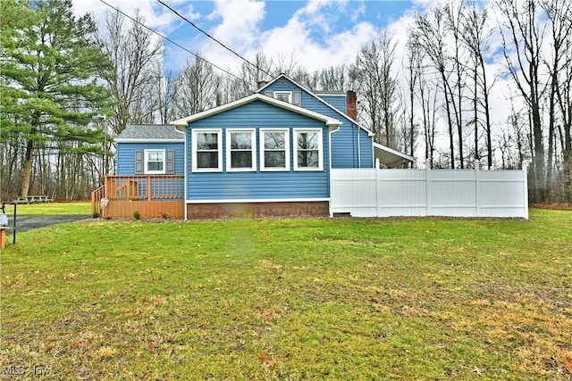 exterior space with a lawn, a chimney, and fence