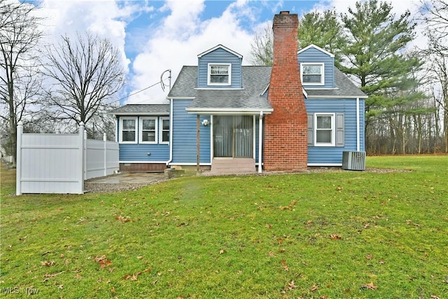 rear view of house with roof with shingles, a chimney, a lawn, fence, and cooling unit