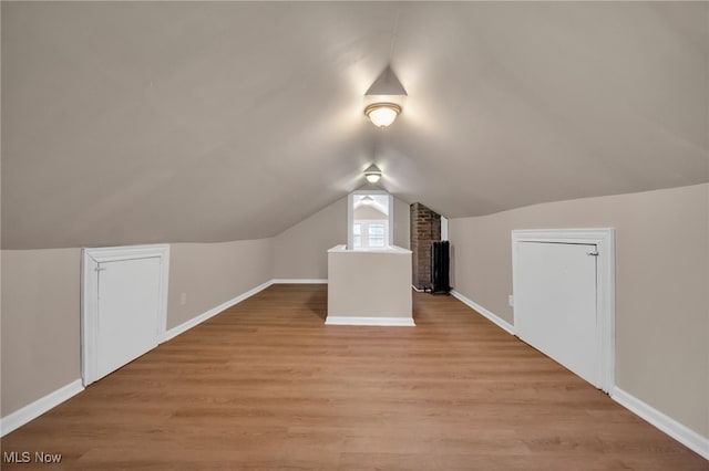 additional living space with lofted ceiling, light wood finished floors, and baseboards