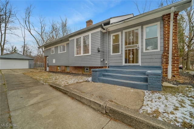 ranch-style home with an outbuilding, a chimney, and a detached garage