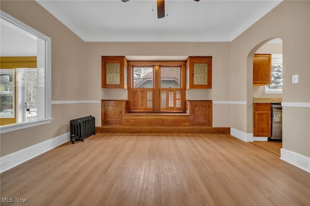 unfurnished living room featuring radiator, light wood-style floors, and plenty of natural light