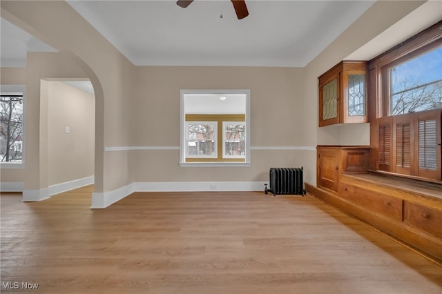 empty room with light wood-type flooring, radiator heating unit, and baseboards