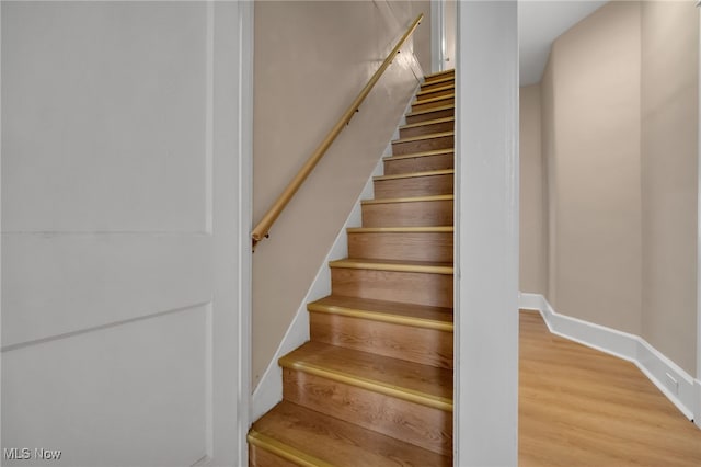 staircase featuring baseboards and wood finished floors