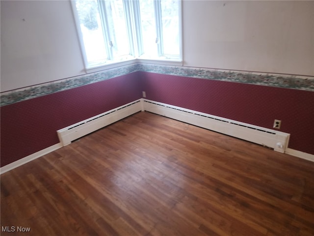 spare room with a baseboard heating unit, wallpapered walls, and wood finished floors