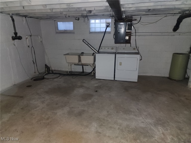 basement with electric panel, washer and clothes dryer, and a sink