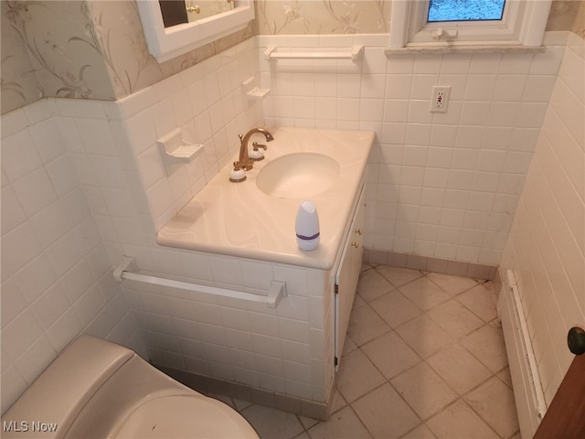 bathroom with a wainscoted wall, tile patterned flooring, vanity, and wallpapered walls