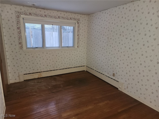 spare room with wallpapered walls and dark wood-type flooring