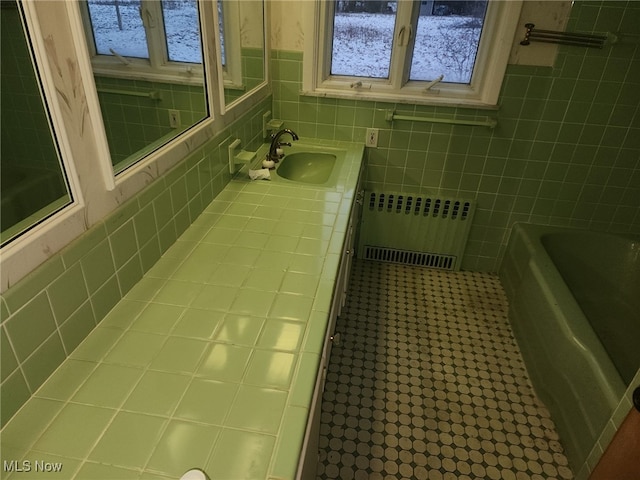 full bath featuring a bathtub, tile walls, radiator heating unit, and vanity