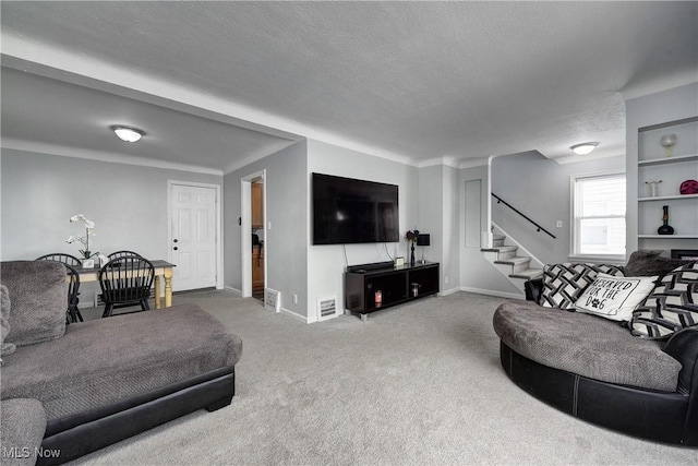 living area with a textured ceiling, carpet floors, stairway, and baseboards